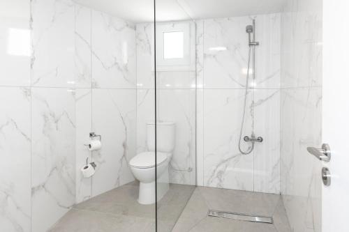 a white bathroom with a shower and a toilet at Blazer Residence in Larnaka