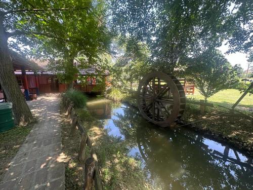 a water wheel sitting in a river next to a fence at Kumova vodenica in Markova Crkva
