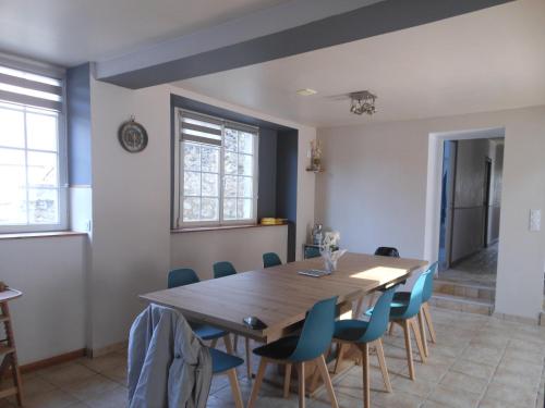 a dining room with a wooden table and blue chairs at LE RABELAIS in Thésée