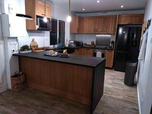 une cuisine avec des armoires en bois et un réfrigérateur noir dans l'établissement M comme Maison à la mer, à La Londe-les-Maures