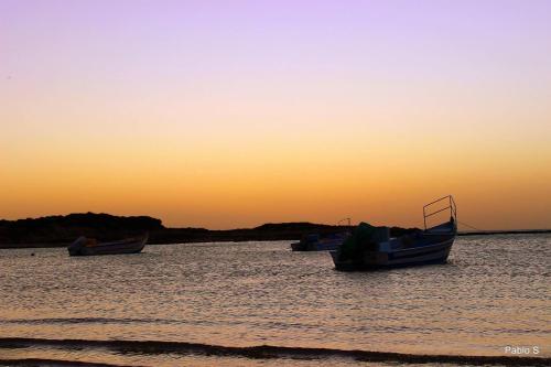 three boats sitting in the water at sunset at Dor village in Dor