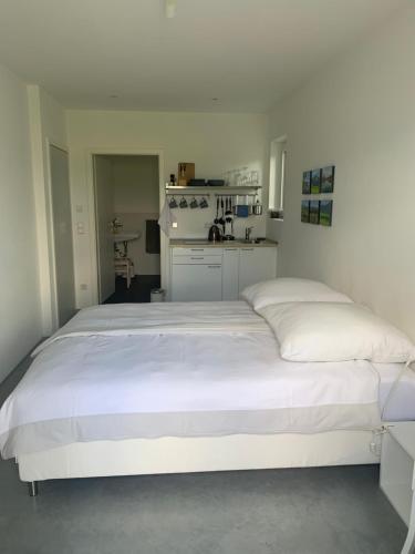 Ce lit blanc se trouve dans un dortoir doté d'une cuisine. dans l'établissement Studio mit Alpenblick, à Kleinweil