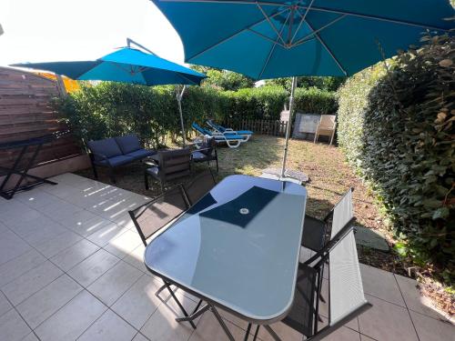 une table et des chaises bleues avec un parasol dans l'établissement Appartement T2 avec jardin privé, piscine et barbecue, à Lorgues