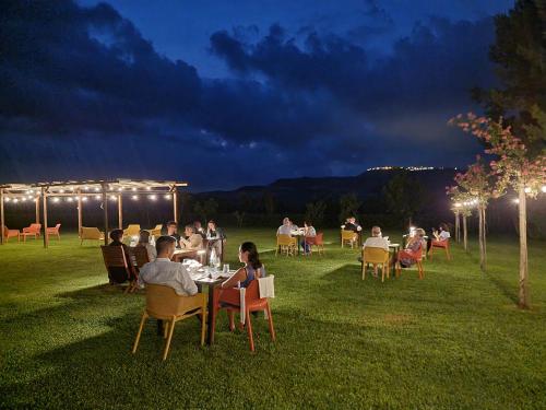 un groupe de personnes assises à des tables dans un champ la nuit dans l'établissement Agriturismo Essentia dimora rurale, à Larino