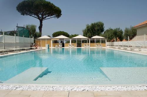 a large swimming pool with chairs and a tree at Sopramare Resort in Piano di Sorrento