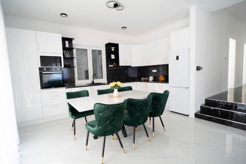 cocina blanca con mesa y sillas verdes en Villa Domino, en Mostar