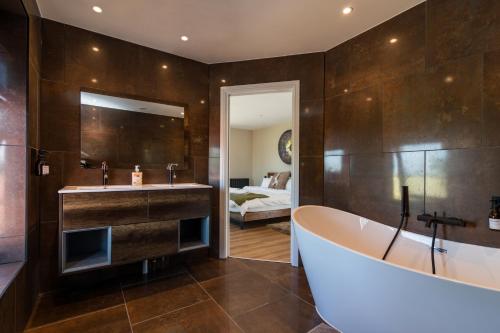 a bathroom with a tub and a sink and a bedroom at Scenic, Getaway Lux House in Countryside Village in Beccles