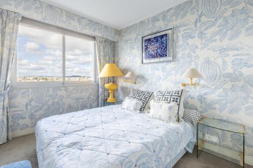 - une chambre bleue et blanche avec un lit et une fenêtre dans l'établissement Luxury Apartment - Paris Eiffel Tower view, à Levallois-Perret