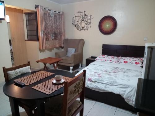 a bedroom with a bed and a table and a chair at Budget Studio Apartment - with Fast Wifi and Netflix in Nairobi