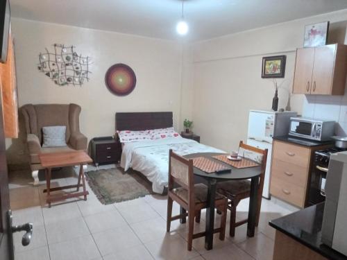 a bedroom with a bed and a table and chairs at Budget Studio Apartment - with Fast Wifi and Netflix in Nairobi