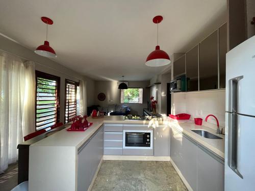 a kitchen with white cabinets and red pendant lights at Bangalôs da Barra Chalé 3 in Barra Grande