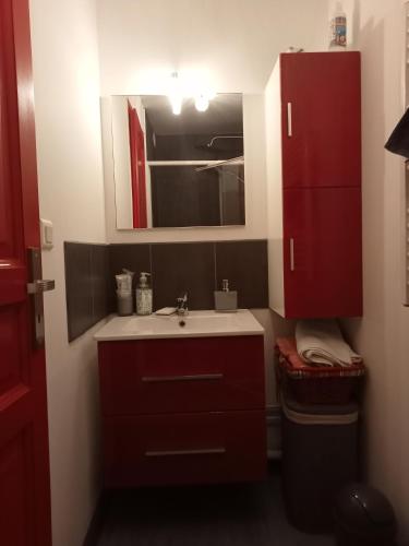 a bathroom with a sink and a red cabinet at Chambre souriante in Lyon