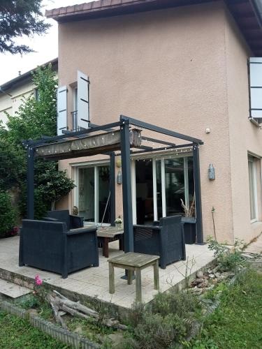 a pergola with a table and benches in front of a house at Chambre souriante in Lyon