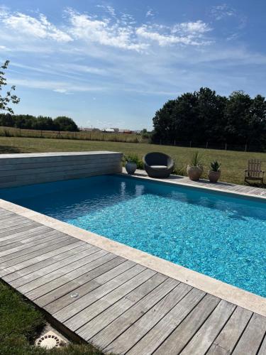 una piscina azul con terraza de madera en Jolie chambre d'hôtes au calme, en Oisly