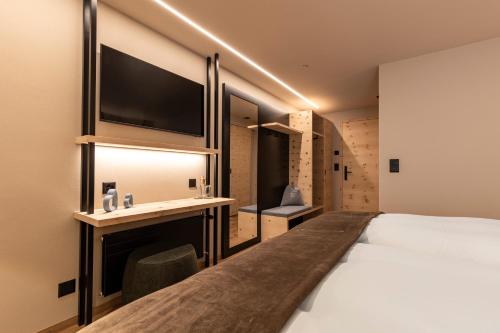 a bedroom with a bed and a desk with a tv at Hotel Baer & Post Zernez in Zernez