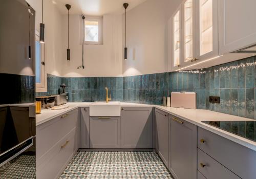 une cuisine avec des armoires blanches et un sol carrelé dans l'établissement L'Appartement du Coin, Beaulieu-sur-Mer, à Beaulieu-sur-Mer