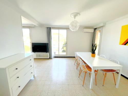 a living room with a white table and a tv at La Cigale du Port in Cassis