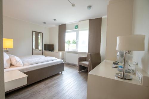 a bedroom with a bed and a desk and a window at Hotel am Tiergarten in Raesfeld