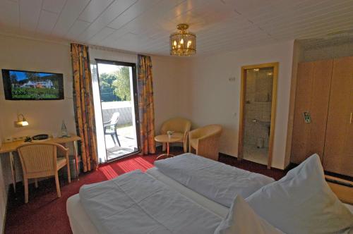 a bedroom with a bed and a table and a chair at Hotel Strand-Café in Roßbach