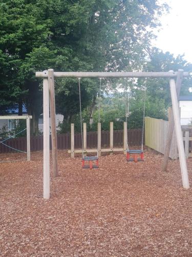 a playground with two swings in a park at Beautiful 3 bedroom holiday home Amazing views in Gisburn