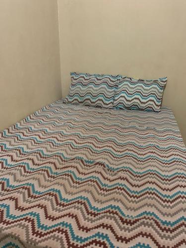 a bed with a striped blanket and a pillow on it at Hospedagem in Barreirinhas
