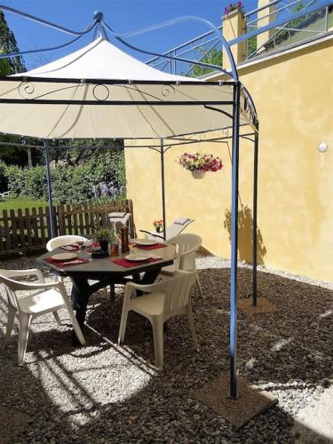 une table et des chaises sous un parasol blanc dans l'établissement Appartement RDC avec terrasse privée, à Castellane