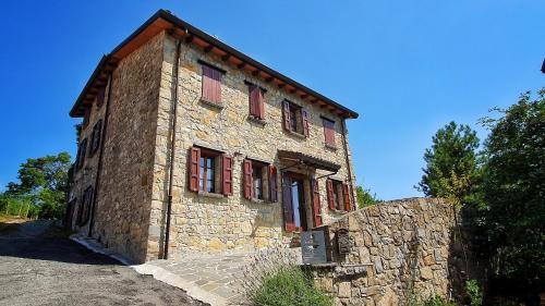 un antiguo edificio de piedra con ventanas de contraventanas rojas en Il Bordone del Pellegrino en Terenzo