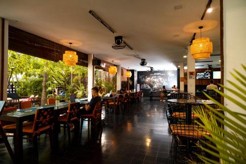 a restaurant with tables and chairs and people sitting at them at Mad Monkey Hostel Phnom Penh in Phnom Penh