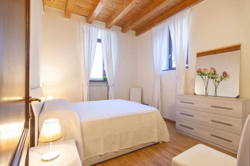 - une chambre avec un lit blanc et un vase de fleurs dans l'établissement Villa Bevilacqua Nuovo bilocale modernopiscina, à Caprino Veronese