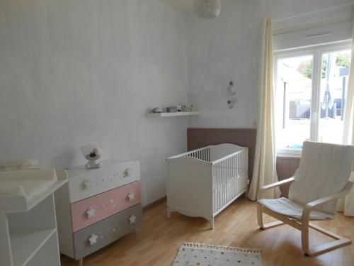 a white nursery with a crib and a chair at LE RABELAIS in Thésée