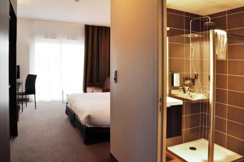 a hotel room with a bed and a bathroom at Golden Tulip Nantes Carquefou Suite in Carquefou