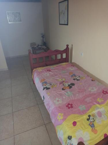 a bed with a pink and yellow blanket on it at Akrotirio Tainaro House in Marmari