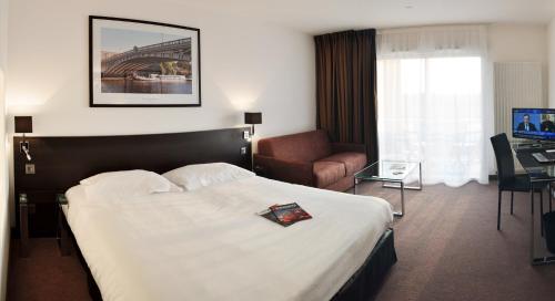 una camera d'albergo con letto, sedia e scrivania di Golden Tulip Nantes Carquefou Suite a Carquefou