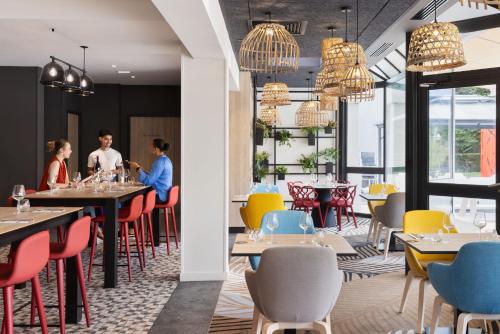 a restaurant with tables and chairs with people sitting at them at Novotel Rennes Alma in Rennes