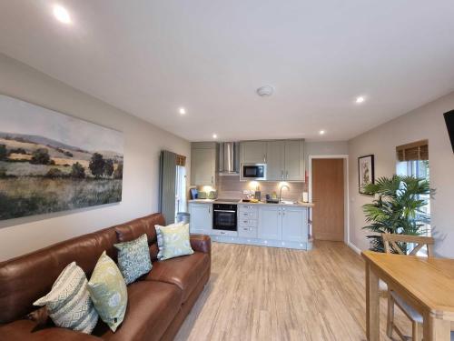 a living room with a brown couch and a kitchen at Chestnut Lodge with Hot Tub in Cupar