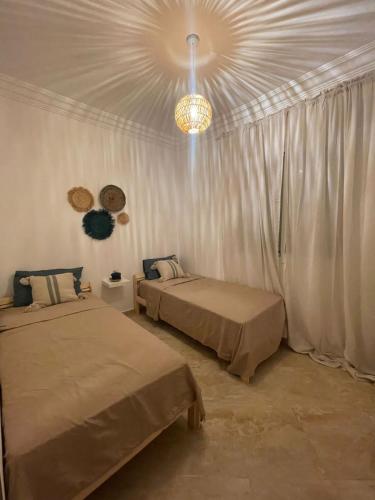a bedroom with two beds and a chandelier at Emplacement idéal : Appartement lumineux El Jadida in El Jadida