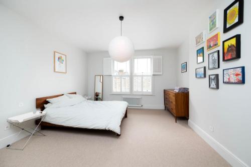 1 dormitorio con 1 cama y cuadros en la pared en Beautiful 4BR Home in Vibrant Haringey en Londres