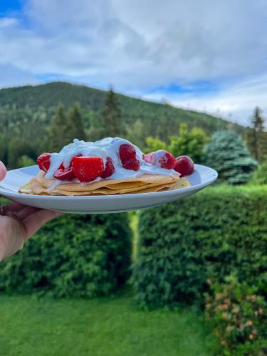 a person holding a plate of food with strawberries on it at Pension Harrachov in Harrachov