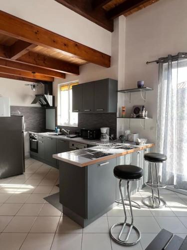 - une cuisine avec un comptoir et deux tabourets dans l'établissement La Petite Angérienne, à Saint-Jean-dʼAngély