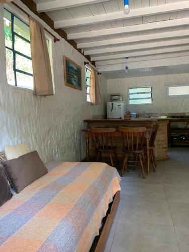 1 dormitorio con 1 cama y cocina con mesa en Morada Sunset Praia do Rosa, en Praia do Rosa