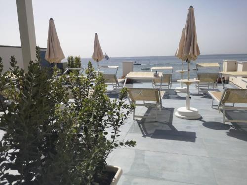 a patio with chairs and umbrellas and the ocean at Tulla's in Giardini Naxos