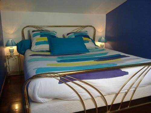 a bed with blue and yellow pillows on it at Au Bois de Massier - Chambre d'hôtes in Vienne