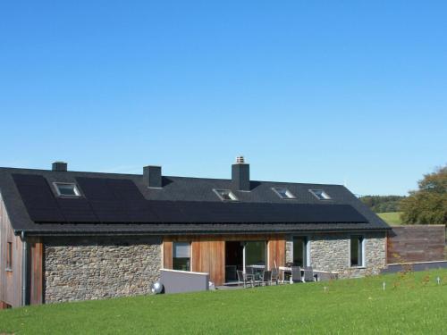 a house with a black roof on a green field at Modern Cottage in Vaux sur S re with Sauna in Morhet