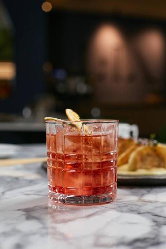 a drink sitting on a table with a plate of food at Pullman Santiago El Bosque in Santiago