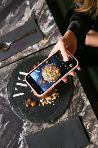 a person holding a cell phone over a plate of food at Pullman Santiago El Bosque in Santiago