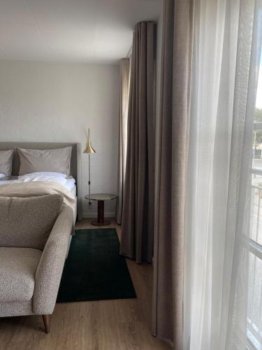 a bedroom with a bed and a chair and a window at Best Western Hotel Herman Bang in Frederikshavn