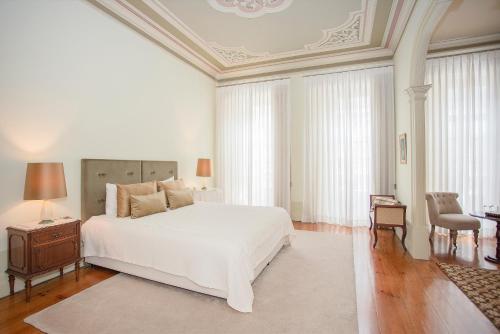 um quarto com uma cama branca, uma mesa e cadeiras em Palace Museum - Espaço Palmeiras em Porto