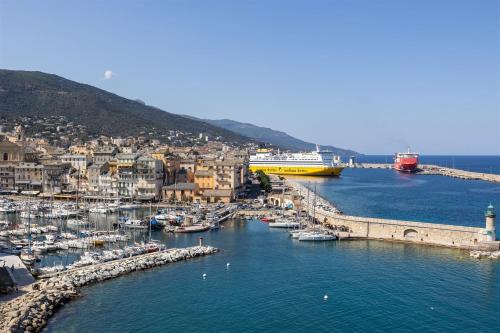 a harbor with boats in the water next to a city at Hôtel Des Gouverneurs in Bastia