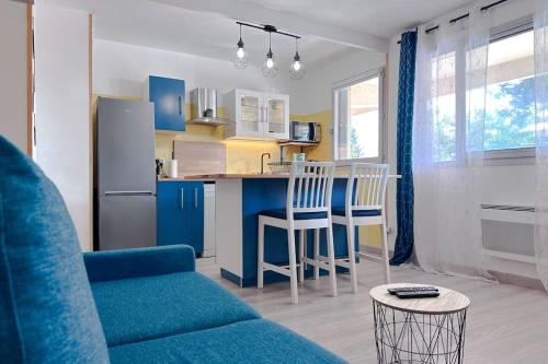uma sala de estar com um sofá azul e uma cozinha em DECAROLI - Stylish and Central Renovated Modern Studio em Saint-Laurent-du-Var