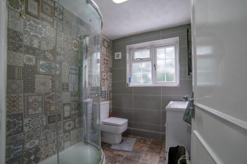 a bathroom with a toilet and a glass shower at Cheerful 3 Bedroom Family Home with parking in Leicester